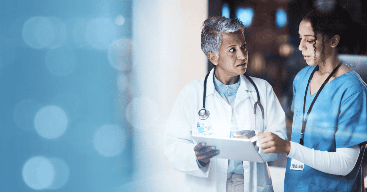 Two healthcare professionals review patient data, representing digital transformation in healthcare.
